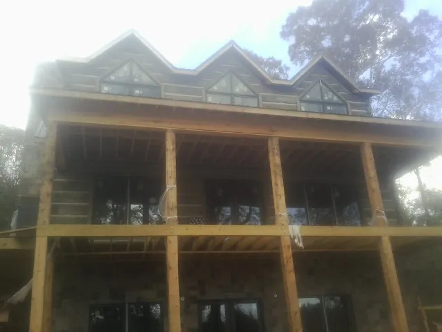 Dormers and porch framing on a large log home under construction — Roof Coating work by our crew in Mount Holly