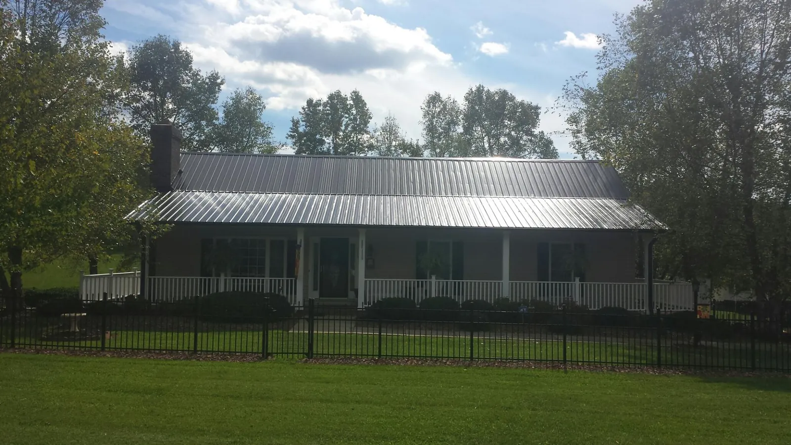 Gray metal roof on a brick ranch with a full width front porch — Gutter Guard Installation work by our crew in Mount Holly